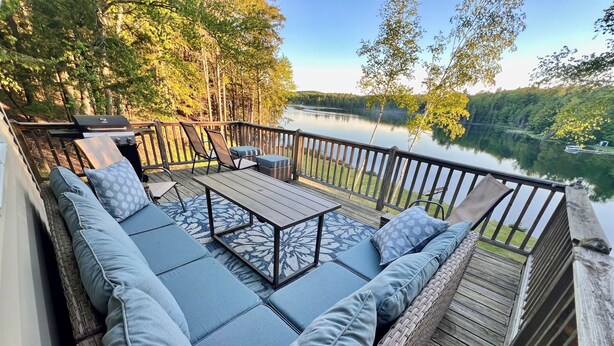 Una terraza con asientos al aire libre, una parrilla y vista al lago.