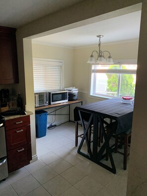 Una cocina con microondas, estufa y mesa de comedor.