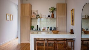 A modern kitchen with wooden cabinets, a marble countertop, and a dining area with wooden chairs. - The Ilium Suite 401 - Luxury 2 bd Suite in Downtown Troy (Troy)