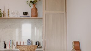 A kitchen with a marble countertop, three wooden stools, a woven basket, and a potted plant. - The Ilium Suite 401 - Luxury 2 bd Suite in Downtown Troy (Troy)