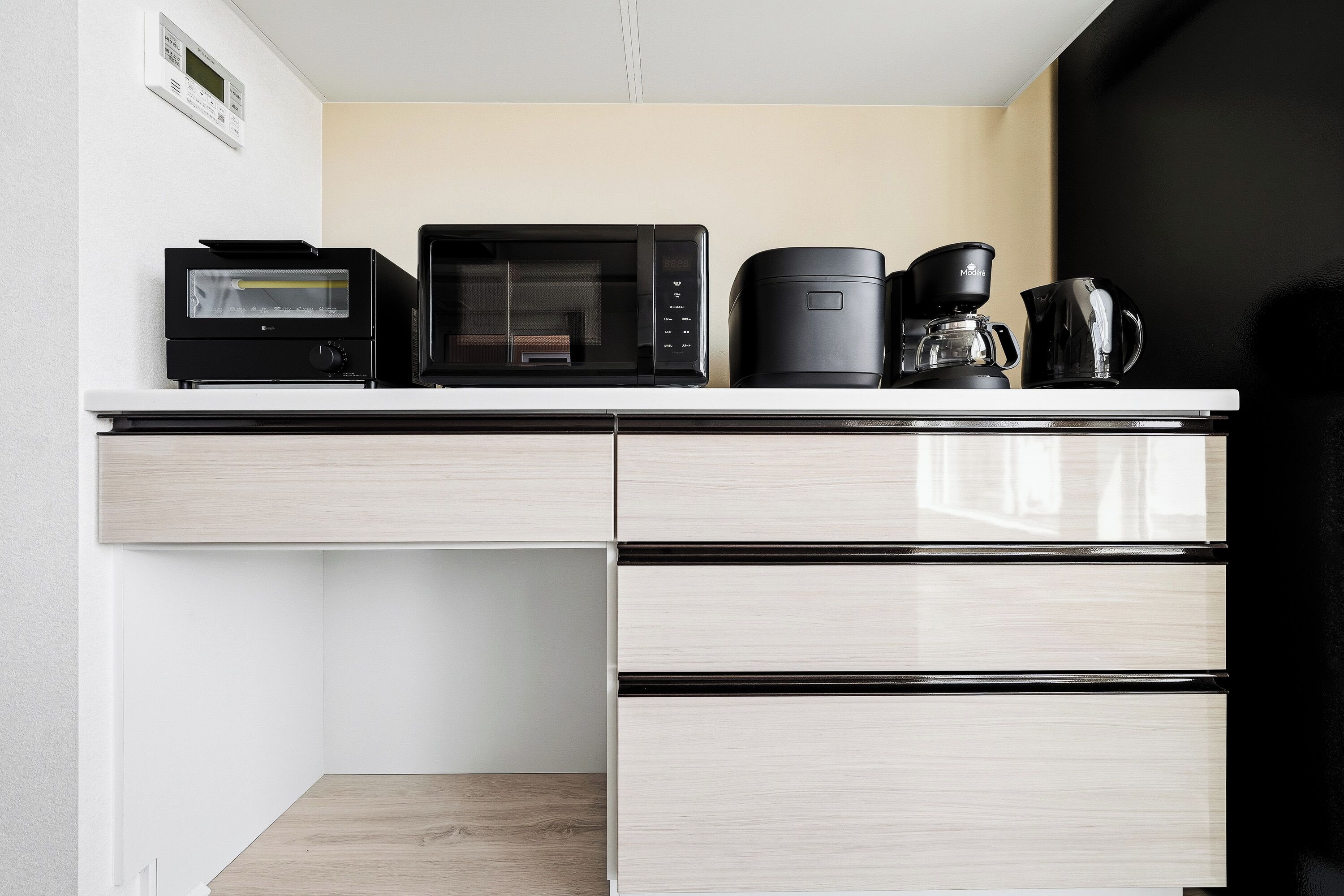 A kitchenette with a microwave, toaster, coffee maker, and a coffee pot on the counter.