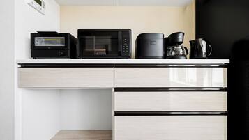 A kitchenette with a microwave, toaster, coffee maker, and a coffee pot on the counter.