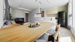 A modern kitchen with a central island, a dining area with a wooden table, and a TV displaying 'NETFLIX' on the wall. - GRACE HOME-A (Sapporo)