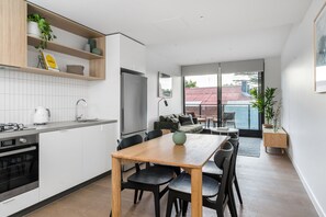 Eine moderne Küche mit Essbereich, einem eingebauten Ofen und einem großen Fenster mit Blick auf ein Gebäude mit rotem Dach.