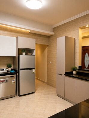 A modern kitchen with stainless steel appliances, a black countertop, and beige tiled walls. - Spacious 4-bedroom apartment in beautiful New Cairo with AC and gym (New Cairo)