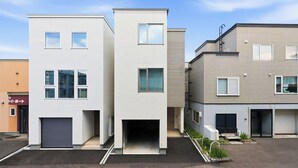 Una hilera de edificios residenciales modernos, de varios pisos, con techos planos, ventanas amplias y puertas de garaje.