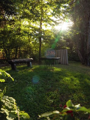 A park with a wooden bench, a metal table, and a corrugated metal structure. - House a few blocks from Nahuel (San Carlos de Bariloche)