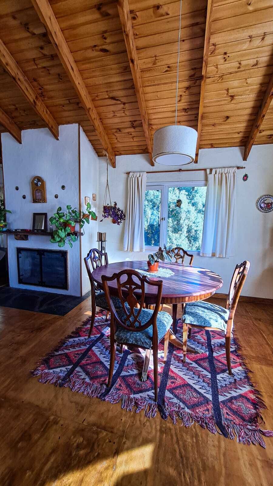 A dining area with a round wooden table, chairs, and a patterned rug.