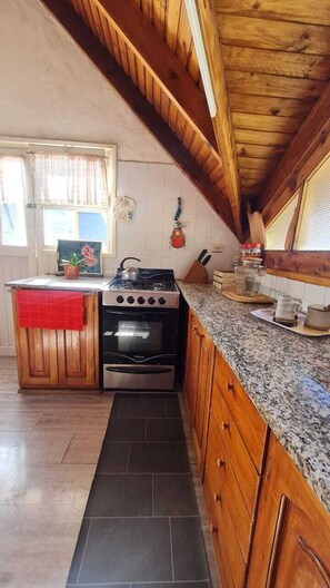 A kitchen with a stove, oven, and granite countertop. - House a few blocks from Nahuel (San Carlos de Bariloche)