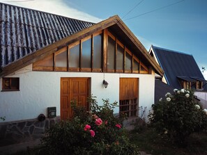 Ein traditionelles Haus mit einem steilen Satteldach, Holzfenstern und einem Steinfundament.