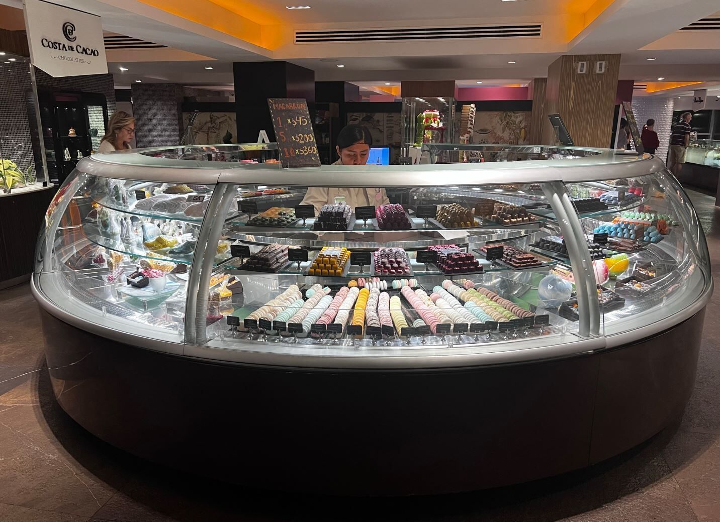 A chocolate display case in a store with a sign above it.