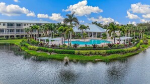 A resort with a swimming pool, palm trees, and a lake. - 3BR, 3BA Placida condo at Landings at Coral Creek (Placida)