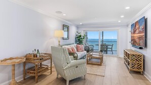 A spacious living room with a balcony, wicker furniture, and a large TV. - 2BR, 2BA Boca Grande condo with ocean views. (Boca Grande)