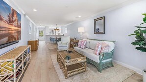 A spacious living room with a large painting, a dining area, and a kitchen in the background. - 2BR, 2BA Boca Grande condo with ocean views. (Boca Grande)