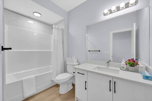 Une salle de bain moderne équipée d’une douche, de toilettes, d’un meuble-lavabo et d’un grand miroir avec éclairage.
