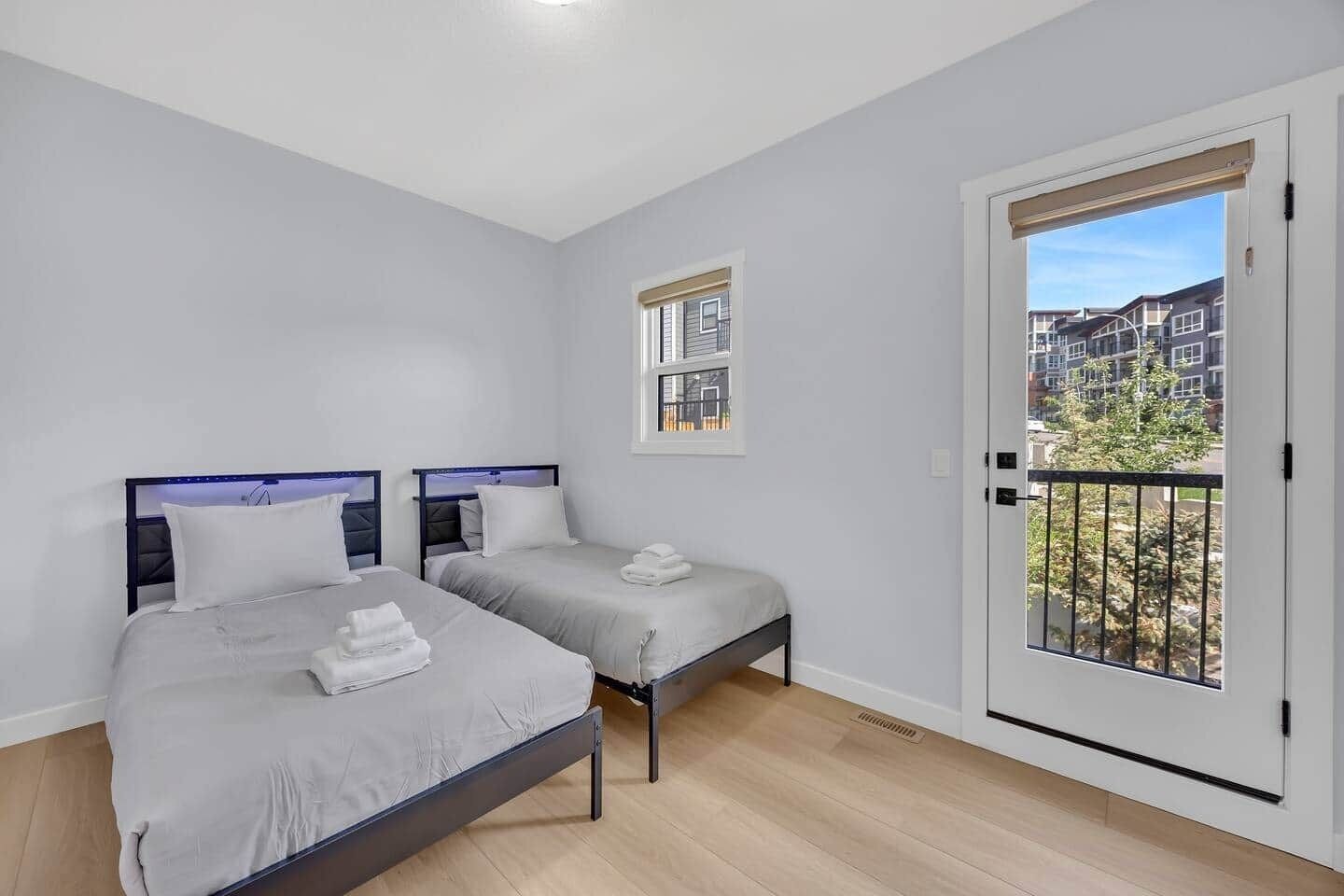 A bedroom with two beds, a window, and a balcony.