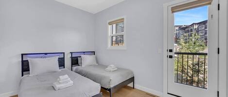 A bedroom with two beds, a window, and a balcony.