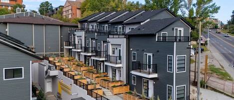 A modern apartment building with multiple balconies, wooden planters, and a clear view of the street.