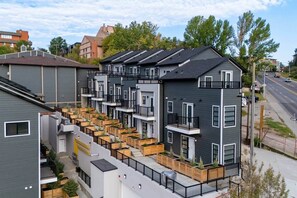 A modern apartment building with multiple balconies, wooden planters, and a clear view of the street. - 301- City Skyline View (Calgary)