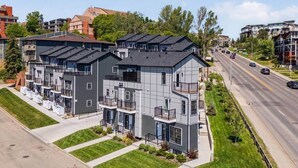 Een meerlaags appartementencomplex met balkons, een oprit en een weg met voertuigen.