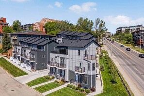 A multi-story residential building with balconies, a driveway, and a road with vehicles. - Crescent Heights Retreat (Calgary)