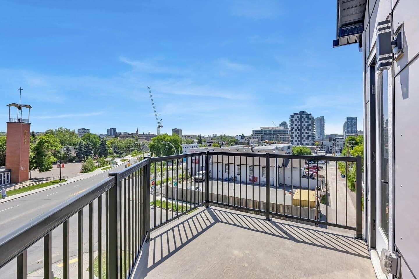 A balcony with a view of a cityscape, including buildings and a crane.