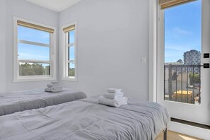 Ein Hotelzimmer mit zwei Betten, einem großen Fenster und Blick auf die Stadtlandschaft.