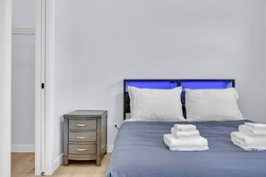 Quarto de hotel com cama, mesa de cabeceira e porta.