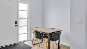 A room with a wooden table, two chairs, a door with frosted glass panels, and a light switch on the wall. - Crescent Heights City view (Calgary)
