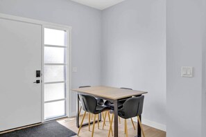 A room with a wooden table, two chairs, a door with frosted glass panels, and a light switch on the wall. - Crescent Heights City view (Calgary)