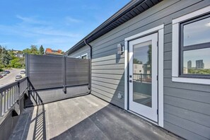A residential building with a sliding glass door, a covered outdoor area, and a view of the cityscape. - Crescent Heights City view (Calgary)