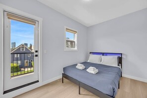 A bedroom with a bed, two windows, and a view of a house. - Crescent Heights City view (Calgary)