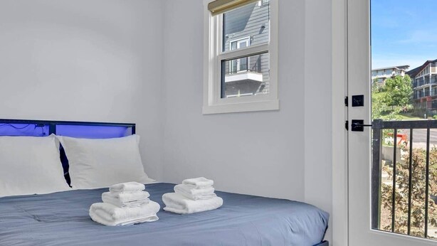 A bedroom with a bed, pillows, and a window. - Crescent Heights City view (Calgary)