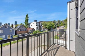 Un quartier résidentiel avec des maisons, un ciel dégagé et un balcon doté d’une rambarde en métal.