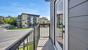 A residential building with a balcony, a road, and other buildings in the background. - Crescent Heights City view (Calgary)