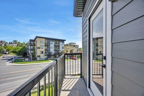 A residential building with a balcony, a road, and other buildings in the background. - Crescent Heights City view (Calgary)