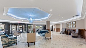 A spacious lobby with a high ceiling, a central chandelier, and a seating area with sofas and chairs. - Stunning Oceanview Retreat | Onsite Dining and Sauna | M609 (Myrtle Beach)