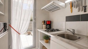 A modern kitchen with a gas stove, a coffee maker, and a sink. - Stunning apartment in Royan with WiFi (Royan)