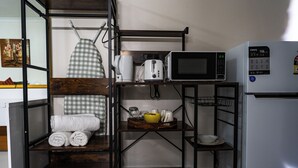 Una kitchenette compacta con microondas, tostadora y refrigerador.