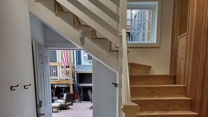 A staircase leading to a second floor, a door to an outdoor area, and a window with a view of the outside.