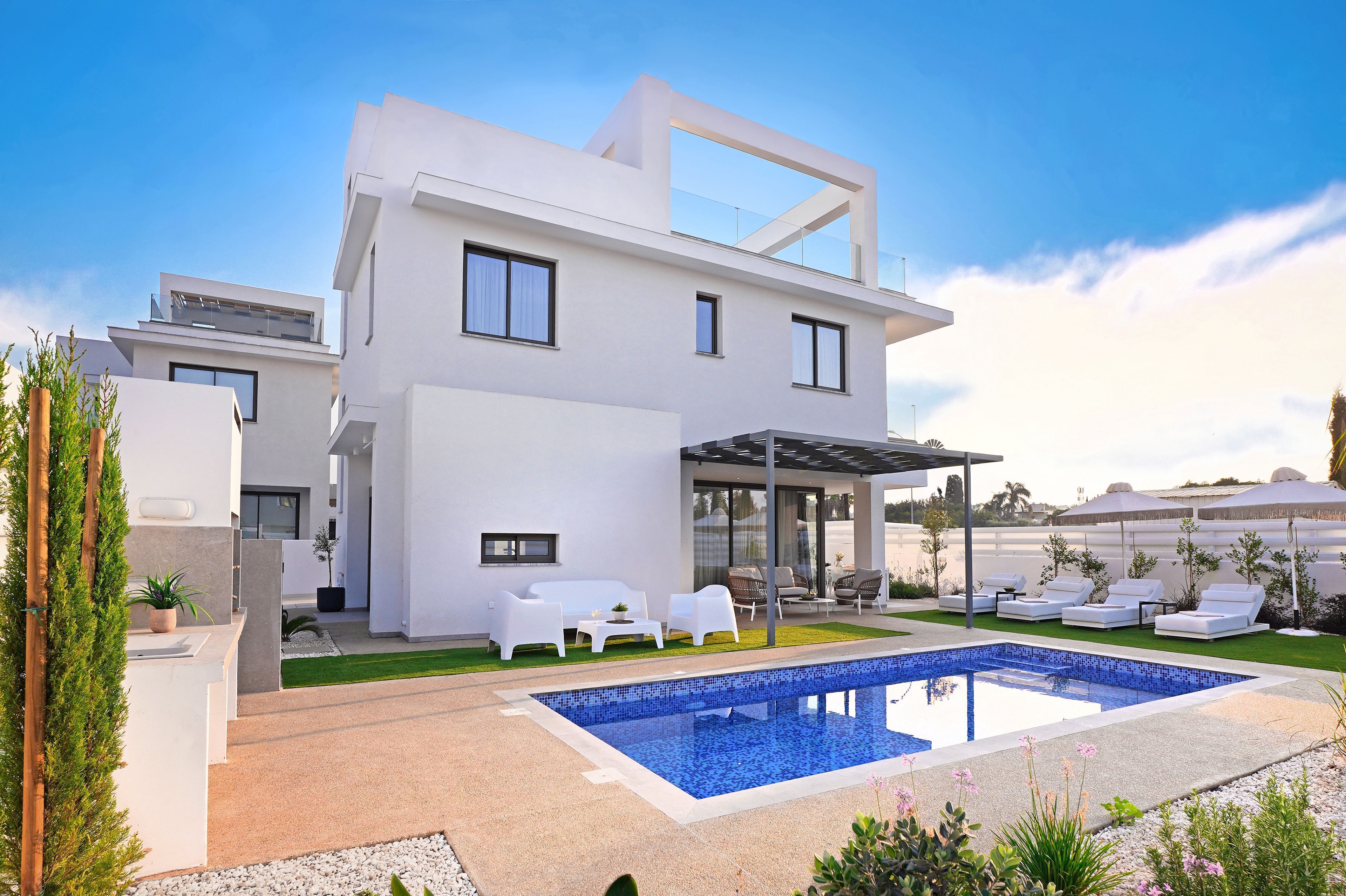 Une maison moderne à deux étages dotée d’une piscine, d’un espace salon extérieur et d’un patio couvert.