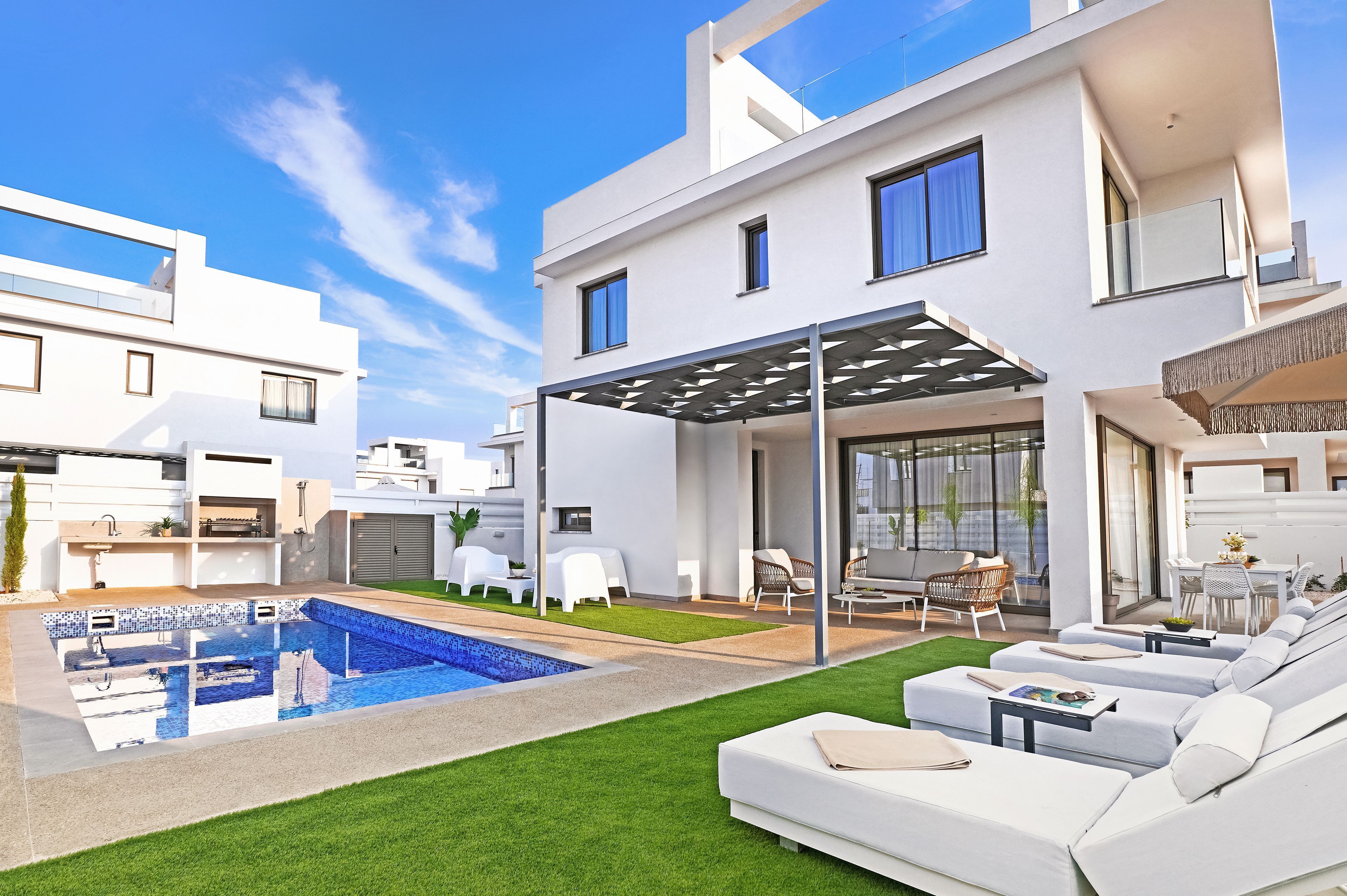 A modern house with a swimming pool, outdoor seating, and a covered patio.