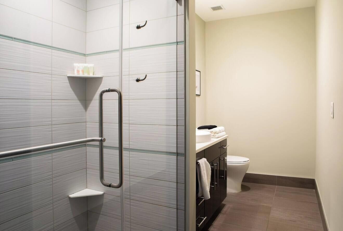 Un baño moderno con cabina de ducha de vidrio, un inodoro blanco y un perchero para toallas.