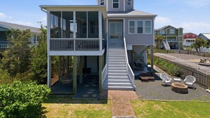 Ein zweigeschossiges Haus mit Balkon, Treppe und einer Terrasse mit Gartenmöbeln.