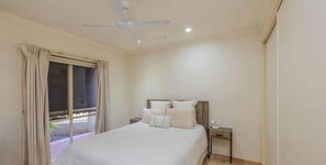 A bedroom with a bed, a nightstand, a ceiling fan, and a window with curtains. - Central Mildura Townhouse – 2BR Walk to City Heart (Mildura)
