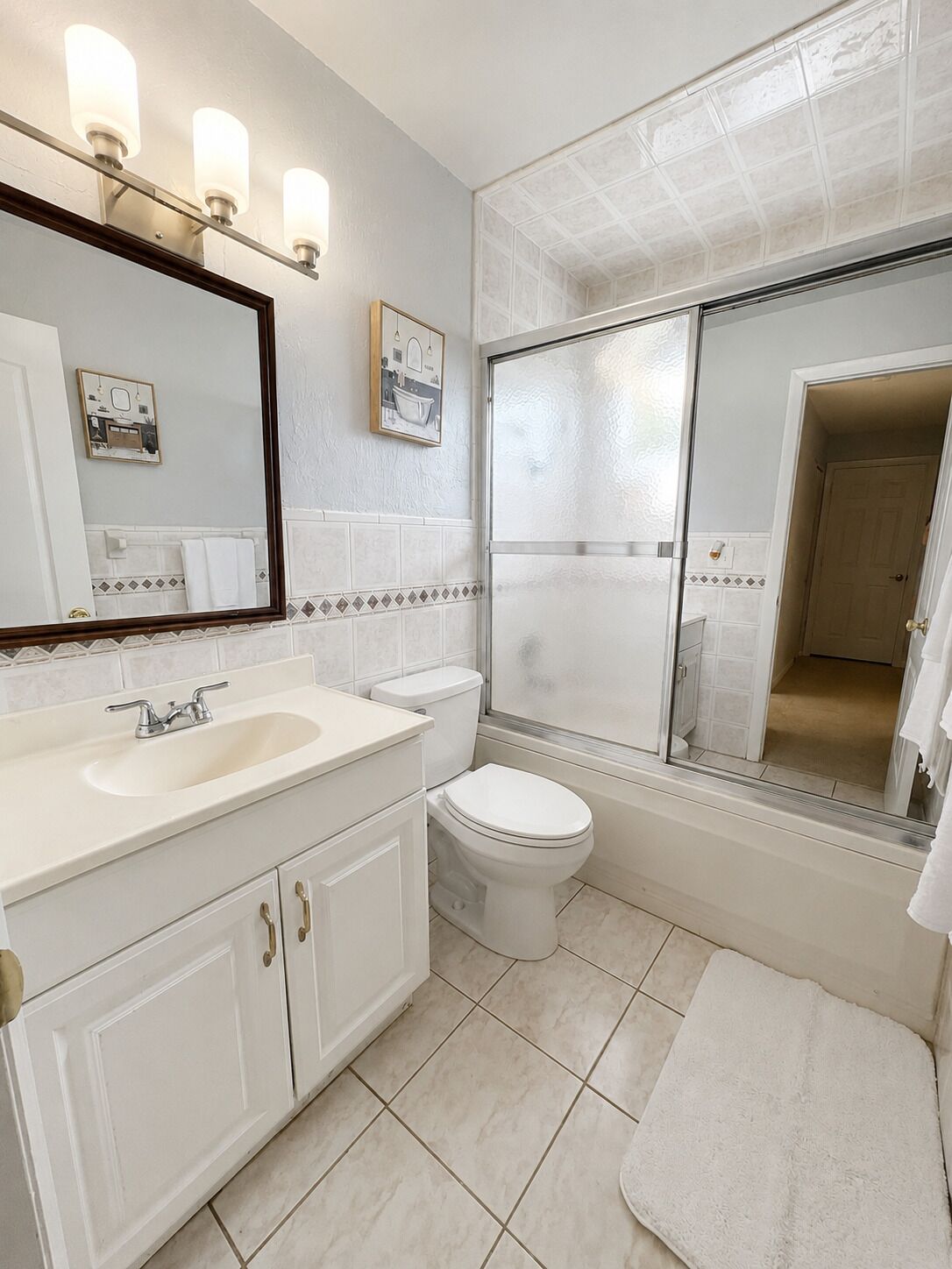 A bathroom with a sink, toilet, and a glass shower enclosure.