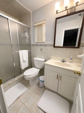 Ein Badezimmer mit Dusche, Toilette, Waschbecken und Spiegel.