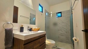 Un bagno moderno con un mobile lavabo, un water, una doccia e un grande specchio.