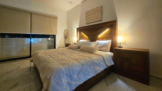 Una camera da letto con un letto, lampade da comodino, una testiera e una finestra.