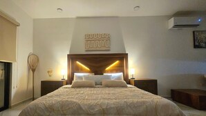 Una camera da letto con un letto grande, due comodini, un condizionatore d'aria a muro e un elemento decorativo a parete.